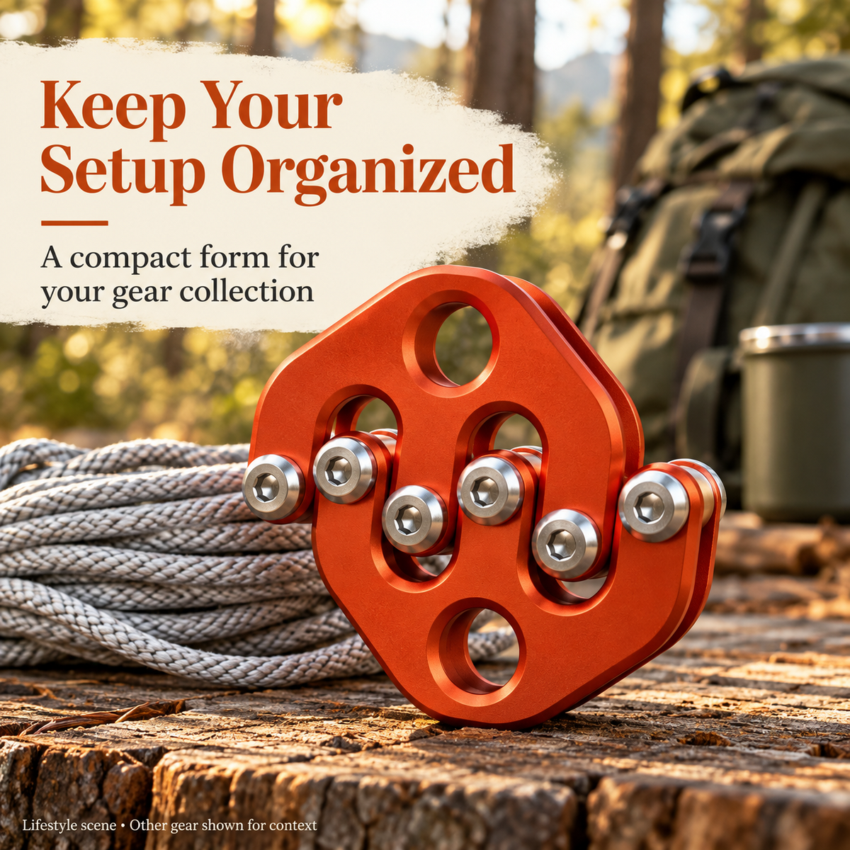 Orange-red multi-roller pulley displayed with coiled rope and outdoor equipment on a wooden surface